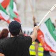 Man holding Iranian flag at women’s rights protest