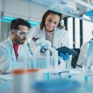 Modern Medical Research Laboratory, Young Scientists Using Microscope, Digital Tablet, Doing Sample Analysis, Talking. Diverse Team of Specialists work in Advanced Lab.