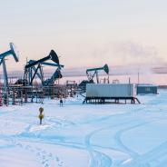 Oil Field. Winter industrial landscape with an oil pump and torch in the background. 