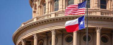 A close-up of the Texas Capitol building and the U.S. and Texas flags.