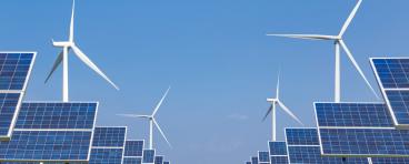 Windmills and solar panels in a grass field.