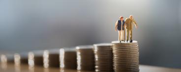 Two old people standing on a stack of coins.