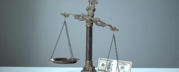 Money weighs down a balance scale.