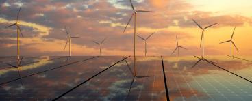 Wind turbines and solar panels against a sunset.