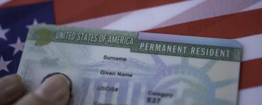A permanent resident card rests on a U.S. flag.