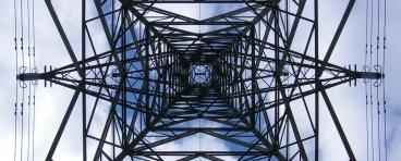 This photo shows an upward view of a transmission tower.