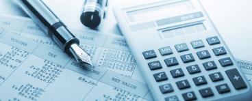 A calculator and fountain pen lie on top of accounting documents.