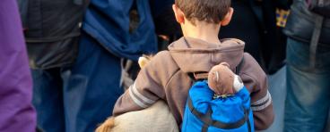 A refugee boy holds a stuffed animal.