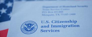 An envelope from the U.S. Citizenship and Immigration Services rests on the U.S. flag.
