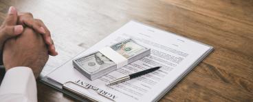 Wad of cash on top of a contract
