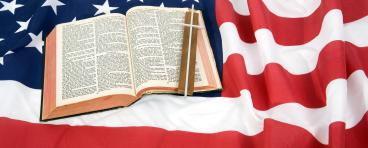 A Bible and the Christian cross on top of an American Flag.