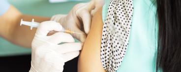 A woman receives a vaccine in her left arm.