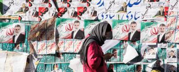 Woman in Iran stands in front of election posters