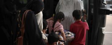 A family of Afghan refugees board a bus.