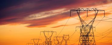 Power lines and transmission towers against a sunset.