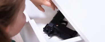 Small child reaches into drawer with firearm