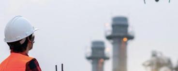 person in safety vest flying drone near power plant