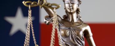 Blind scales of justice with texas flag in background