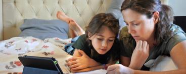 A mother teaches her daughter at home.