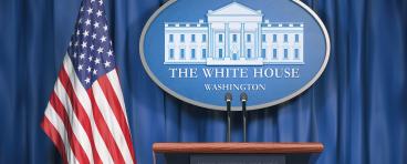 Podium speaker tribune with US flags and sign of White House