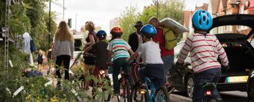 Kids on bikes being led by adults on sidewalk