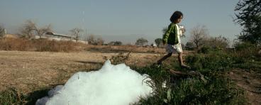 A girl walks by a polluted stream in Cuenavaca.
