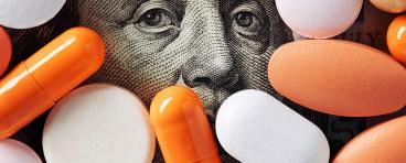Capitalism and healthcare policy concept. Colorful medical pills cover Benjamin Franklin's face on one hundred American dollar bill. Macro top down view.
