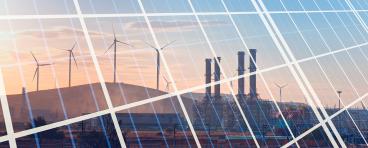 Natural gas processing plant with renewable energy wind turbines generating electricity reflection to solar panels at sunset