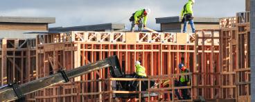  A crew of construction workers atop wooden structures, building a multistory apartment complex in East Mesa, Arizona.