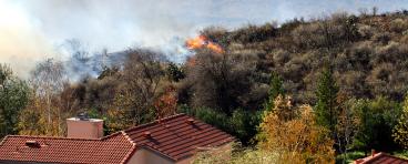 Wildfire erupts near houses on a hill