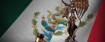 Mexico flag with statue of lady justice, constitution and judge hammer on black drapery. Concept of judgement.