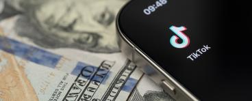TikTok app on smartphone screen with dollar background