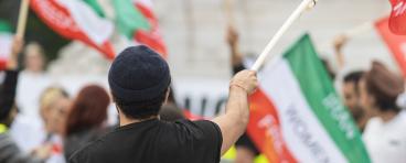 Man holding Iranian flag at women’s rights protest