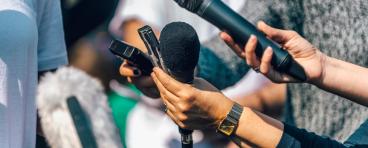 Reporters hold up microphones