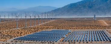 solar panels and wind turbines in desert landscape