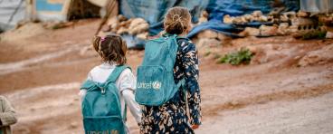Refugee girls wearing UNICEF backpacks
