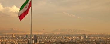 Iran Flag in the Wind Above Skyline of Tehran 