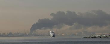 A yacht sails past a plume of smoke rising from the port of Jebel Ali following a reported Iranian strike in Dubai on March 1, 2026.