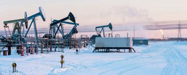 Oil Field. Winter industrial landscape with an oil pump and torch in the background. 
